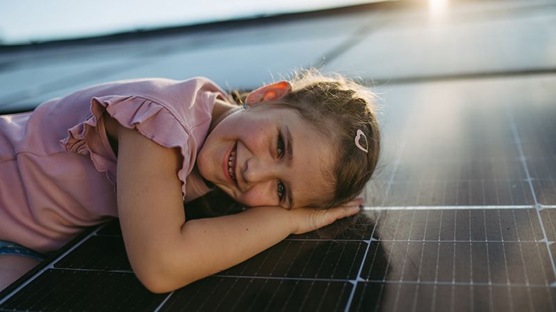 Kleines Mädchen liegt auf Solarmodulen