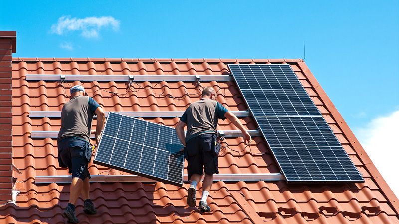 Handwerker installieren Solaranlage auf Dach