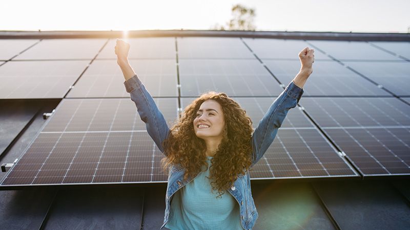 Jubelnde Frau vor Photovoltaikanlage